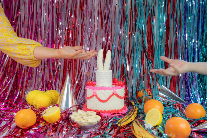 A party scene featuring fun, fruit, and a banana topped cake.