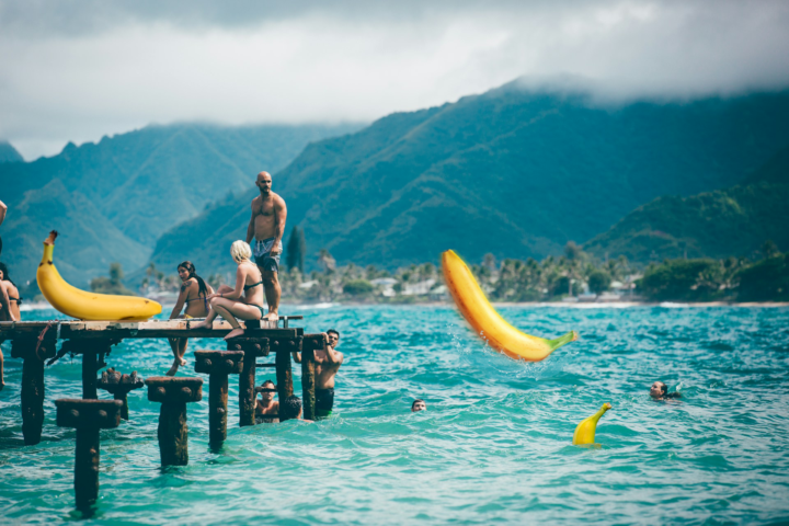 Three bananas join a group of beach goers.