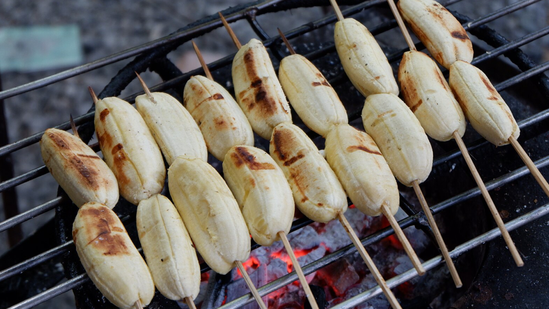 Skewered bananas getting grilled on a bbq.