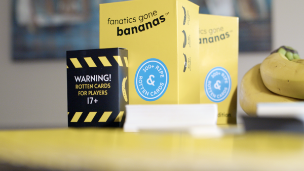A close-shot photo of Fanatics Gone Bananas, including the rotten box, decks of cards, cards fanned out, and a bunch of bananas on a table.