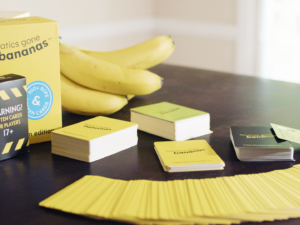 A wide-shot photo of Fanatics Gone Bananas, including the rotten box, decks of cards, cards fanned out, and a bunch of bananas on a table.