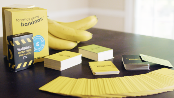A wide-shot photo of Fanatics Gone Bananas, including the rotten box, decks of cards, cards fanned out, and a bunch of bananas on a table.