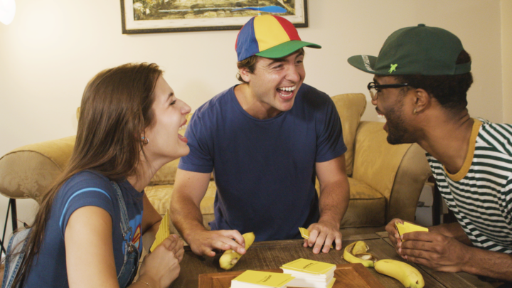 A photo of three people playing Fanatics Gone Bananas in a living room and laughing with each other.