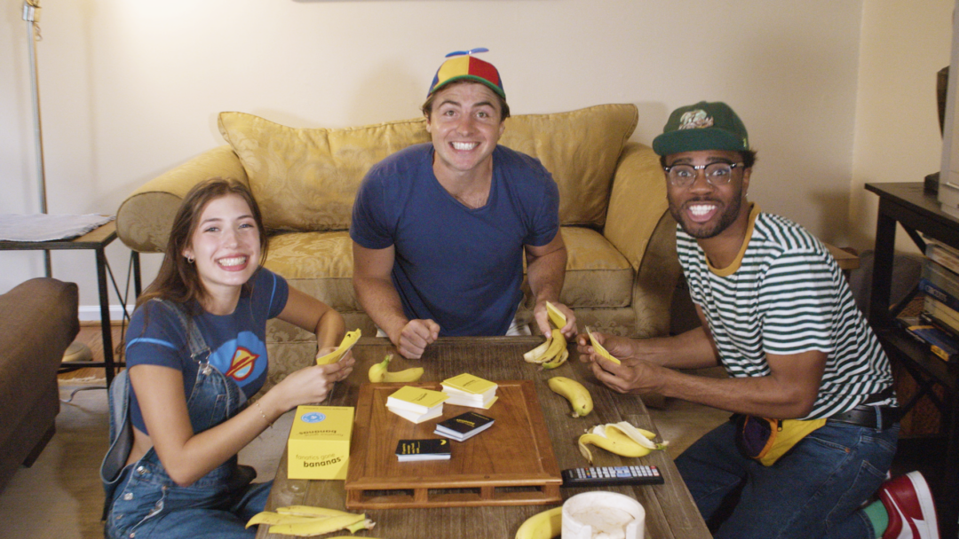 Bananas Players Smile A photo of three people playing Fanatics Gone Bananas in a living room while they smile at the camera.
