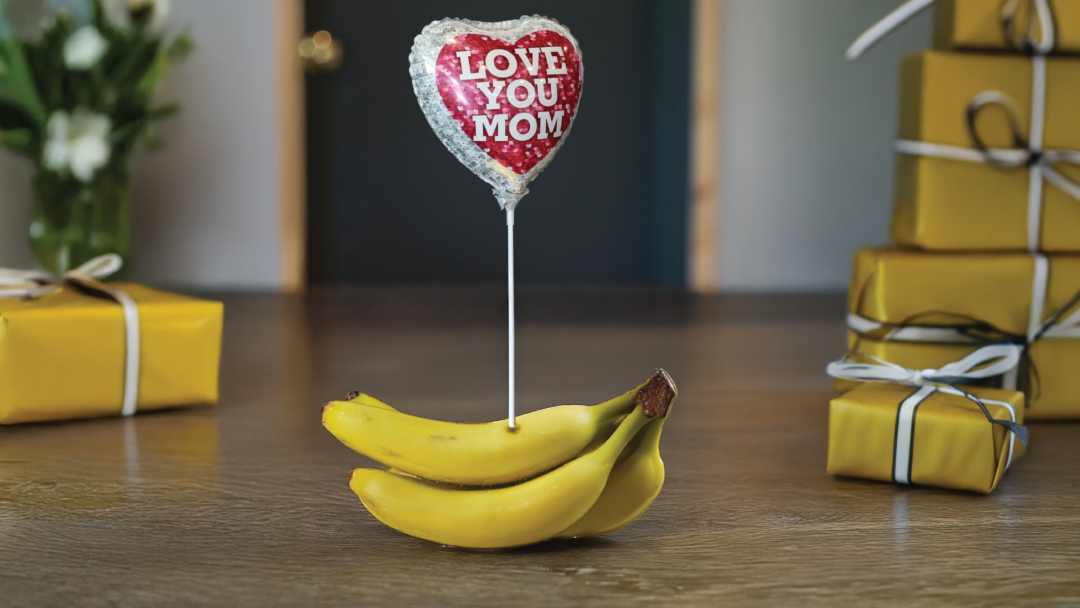 A Mother's Day balloon stuck in a bunch of bananas.
