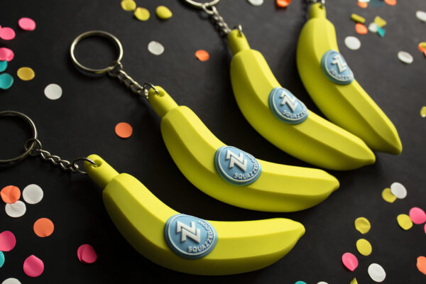 A group of banana-shaped keychains, arranged with confetti.