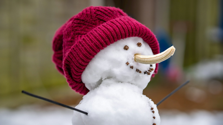 A snowman with a banana for a nose instead of a carrot.