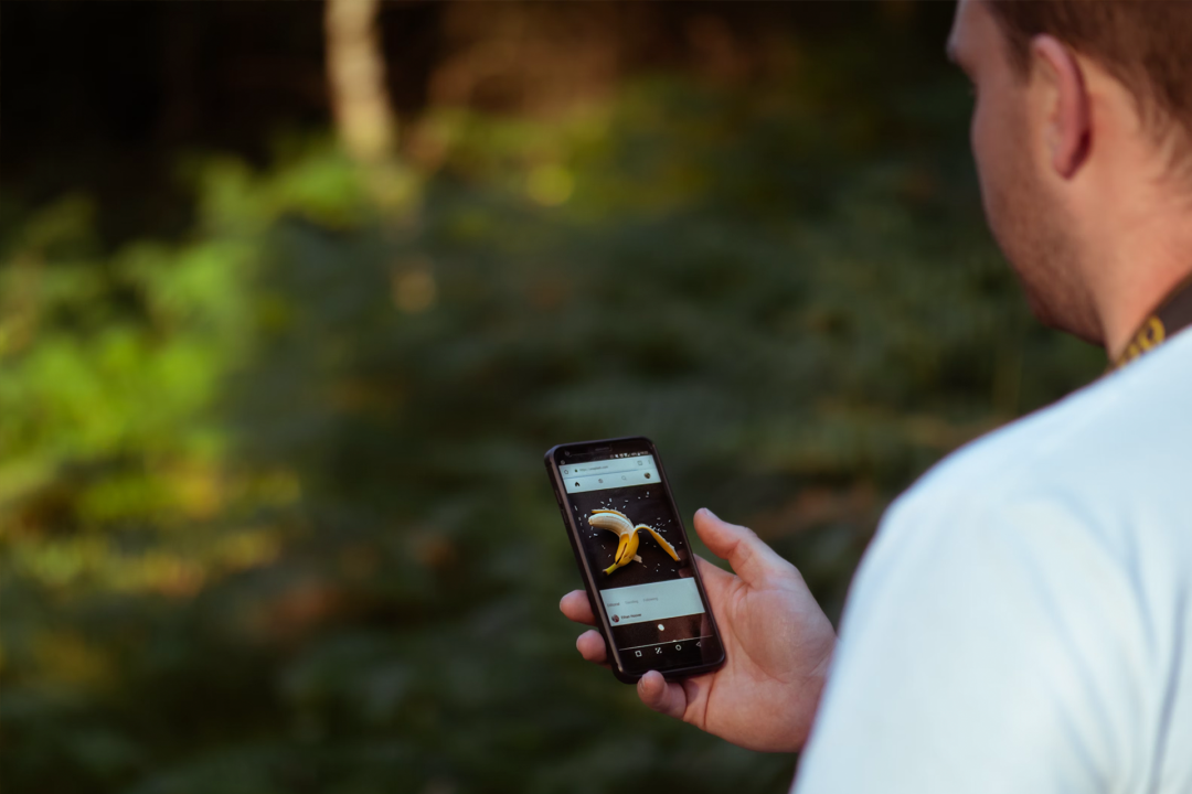 A man watches hot banana content on his phone in a secluded location.