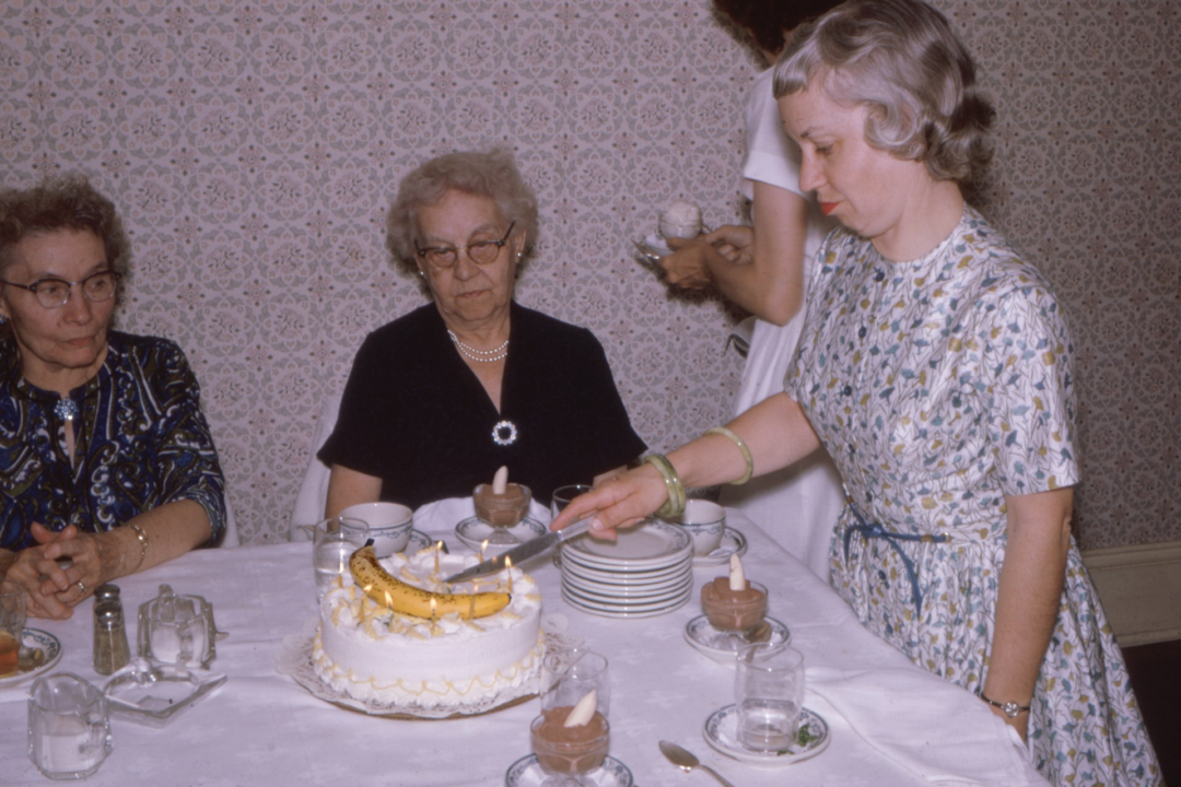 A banana cake is cut at a gathering with Grandparents.