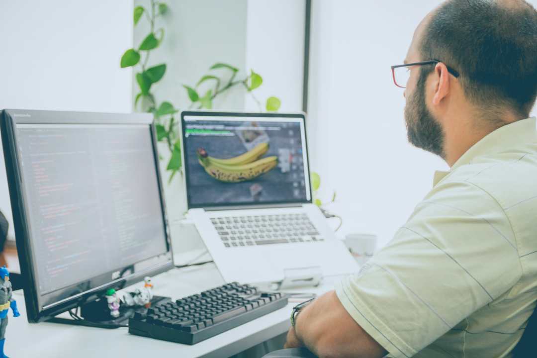 A man working in an office looking at computers.